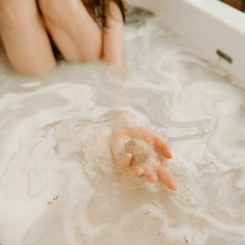 Champagne Apple Bath Bomb fizzing in a clear tub, releasing bubbles and vibrant colors.