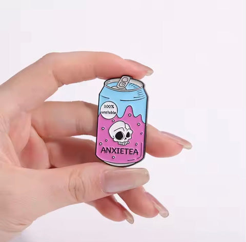 he "Anxietea" enamel pin held in a hand, showcasing its size and design with a cute teacup illustration.